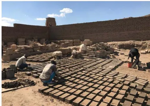 Figure 31: Workers add the mixture (clay & straw) to the mold for making adobe bricks.