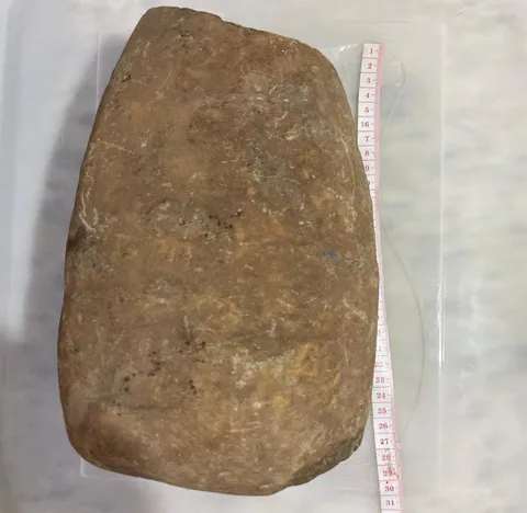 a autora.Esse aretetato arqueológicié uma “mão de pilão”. Material lítico polido (M.L.P.) Comprimento:25 cm. Largura: 15 cm. Espessura: 12 cm. Peso:5.100 kg. Esse artefato tinha um tamanho bem maior . Era utilizado para triturar grãos e raizes.