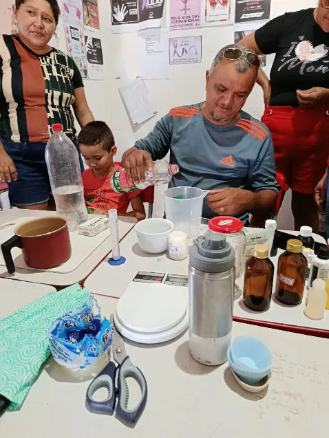Participant measuring and pouring liquid ingredients at a workstation with bottles, jars, and digital scales.