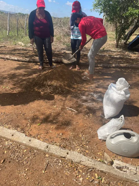 Women using a shovel to mix soil substrate and manure beside fertilizer bags and a watering can.