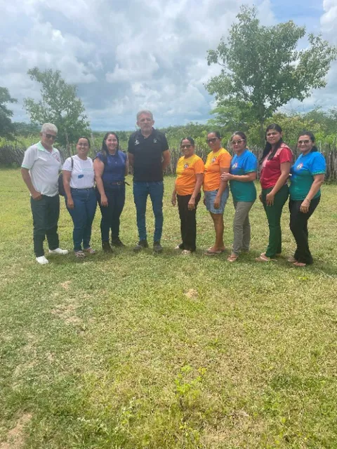 Meeting participants and community board members standing together outdoors in a grassy field.