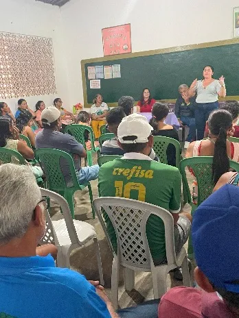 Attendees seated in a classroom listening to a presentation during the community meeting.