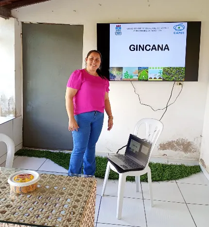 Instructor standing next to the television screen displaying the Gincana quiz competition title.